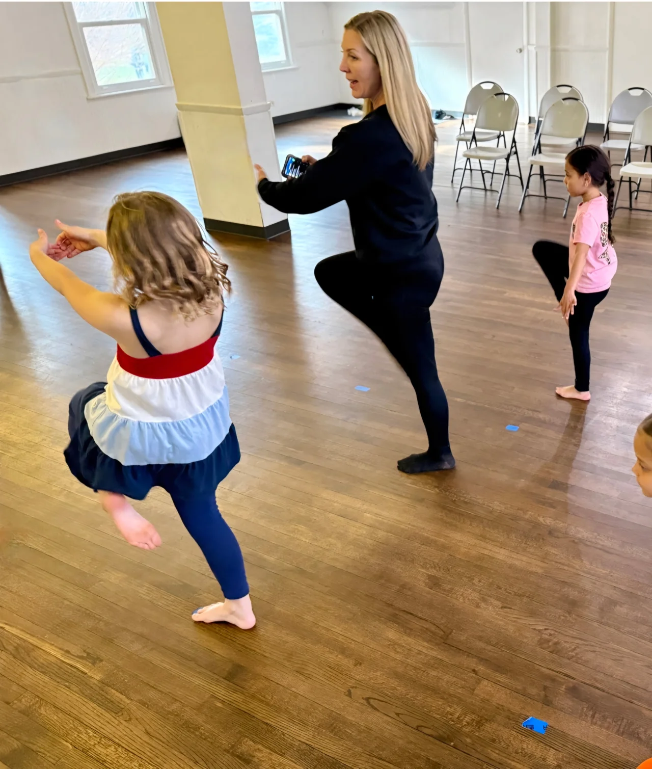 Jessica demonstrating a dance move to a group of children