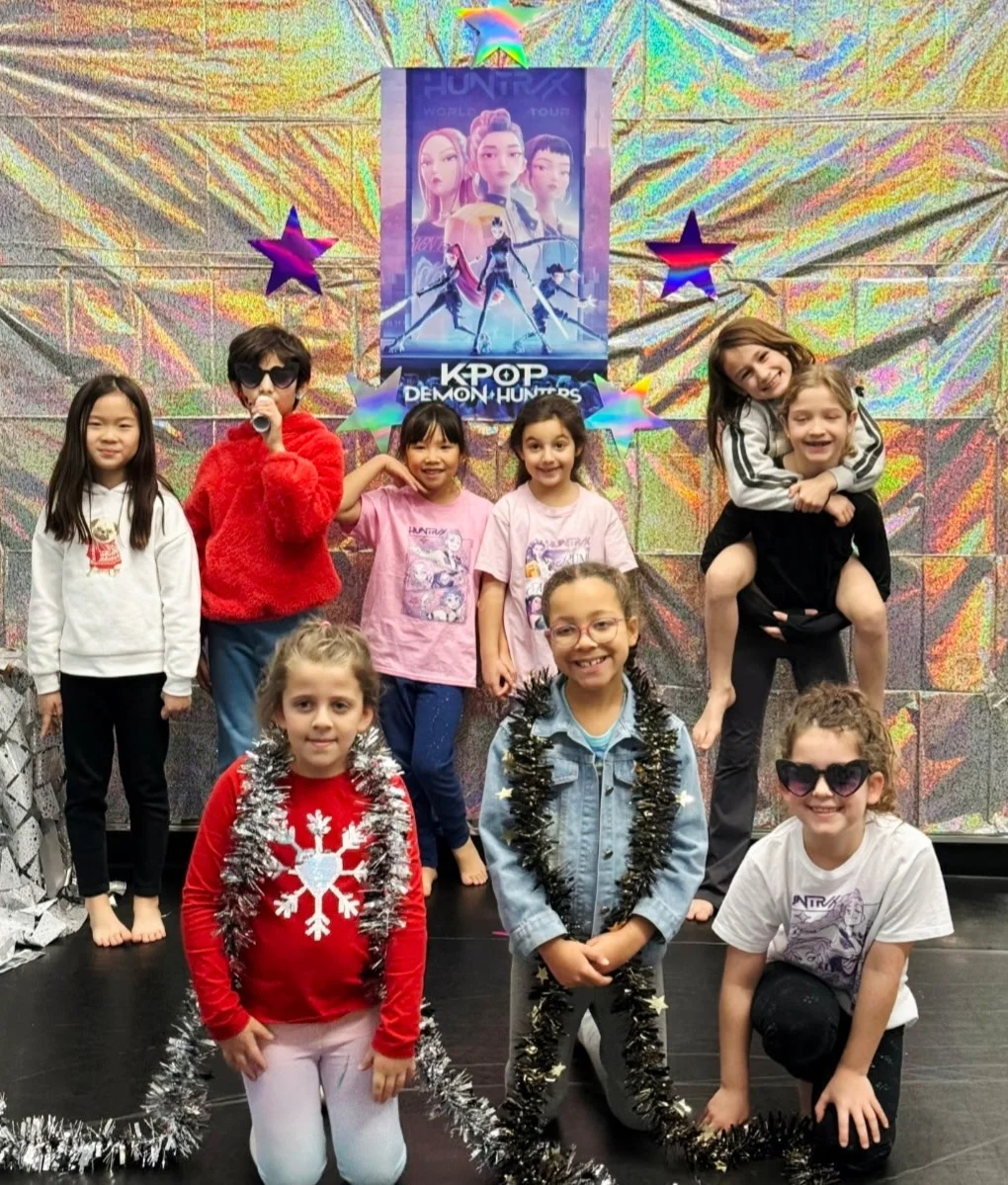A group of children in front of a K-pop dance backdrop